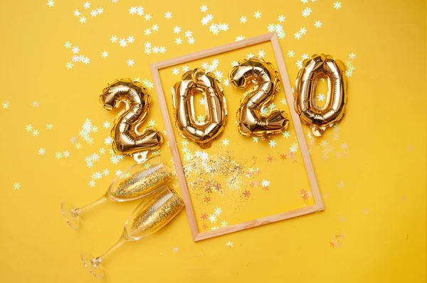 Bolas de lámina dorada sobre fondo amarillo. Cifras inflables 2020. Concepto año nuevo, Navidad. Copiar vista superior del espacio Fotos De Stock