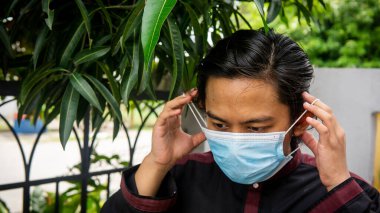 Coronavirus 'taki bayram kutlamasında geleneksel Kurta gömlekli Asyalı genç bir adamın portresi. Üç katlı yüz maskesi takıyor. Hijyen yaşam tarzı. Yeni normal kavram.