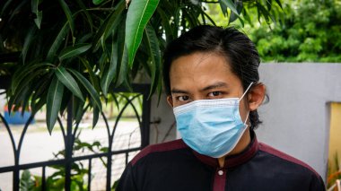 Coronavirus 'taki bayram kutlamasında geleneksel Kurta gömlekli Asyalı genç bir adamın portresi. Üç katlı yüz maskesi takıyor. Hijyen yaşam tarzı. Yeni normal kavram.