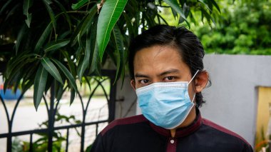 Coronavirus 'taki bayram kutlamasında geleneksel Kurta gömlekli Asyalı genç bir adamın portresi. Üç katlı yüz maskesi takıyor. Hijyen yaşam tarzı. Yeni normal kavram.