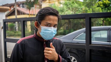 Coronavirus 'taki bayram kutlamasında geleneksel Kurta gömlekli Asyalı genç bir adamın portresi. Üç katlı yüz maskesi takıyor. Hijyen yaşam tarzı. Yeni normal kavram.