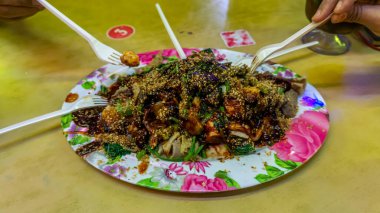 İnsanlar Yong Tau Foo ya da Yentafu 'yu yiyorlar. Masada plastik çatal kullanan bir Çin mutfağı. Köfte ya da balık ezmesi ile doldurulmuş tofu içeriyor. Resim gürültü ve seçici odaklanma içeriyor.