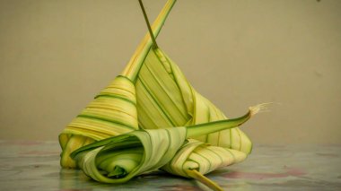 Pişmemiş Malay yemeği Ketupat Daun Palas ya da glüten pirincin fan palmiyesi yaprakları kullanılarak üçgen şeklinde sarıldığı pirinç köftesi. Genellikle Mübarek bayramında ya da Hari Raya kutlamalarında bulunur..