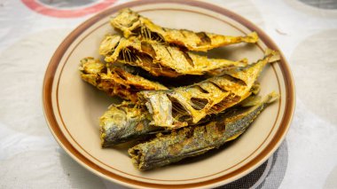 Masa arkasındaki tabakta servis edilen kızarmış uskumru balığının yakın görüntüsü. Geleneksel Malezya öğle yemeği için yemek servis etti.