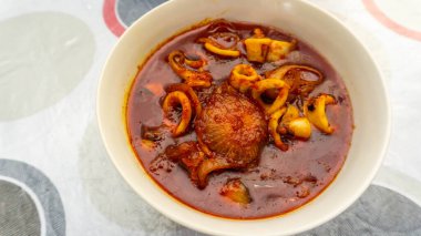 Masanın üzerinde beyaz bir kasede servis edilen acı biber soslu kızarmış kalamar tabağını yakından izleyin..