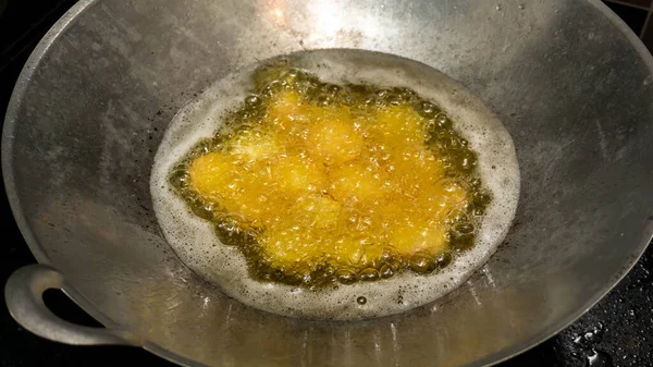 Close up view of raw soft tofu being deep fry in a metal wok at the kitchen. Soft tofu is the Chinese-style equivalent of silken tofu. Image is bit out of focus.