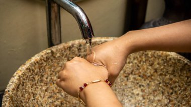 Musluktan akan suyun altındaki lavaboda elini temizleyen kızın yakın görüntüsü. Kirli bakterilerden, virüslerden ve mikroplardan korunmak için. Sağlıklı yaşam tarzı kavramı. Seçili odak.