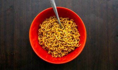 Kızarmış eriştenin üst görüntüsü mü yoksa ahşap arka planda çatallı Maggie mi? Seçici odaklanma. Biraz gürültü içerir.