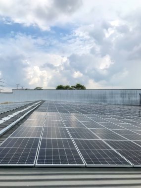 Fotovoltaik enerji santrali veya güneş parkının güneş panellerini bir fabrikanın çatısına elektrik sağlamak için görüntüleyin. Yenilenebilir enerji ve alternatif elektrik kaynağı. Seçici odak.
