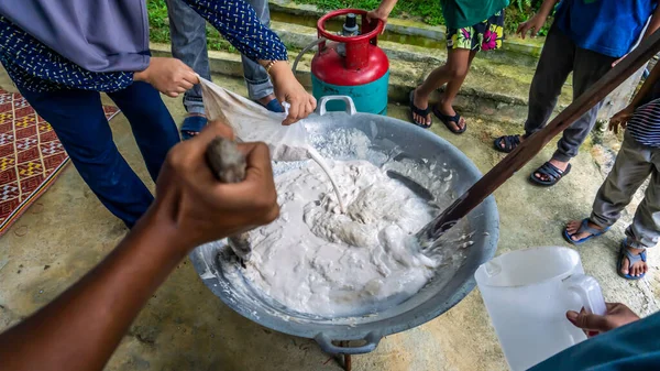 Cooking traditional Malaysian sweet desert, Dodol by the villagers during Hari Raya. It is a sweet toffee-like sugar palm-based confection. Selective focus. Contains a bit of noise.