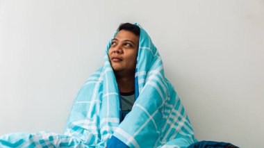 Mutlu Asyalı bir adamın portresi. Sabahları üşüyüp battaniyenin altında yatarken. Uykudan uyandıktan sonra tazelik.