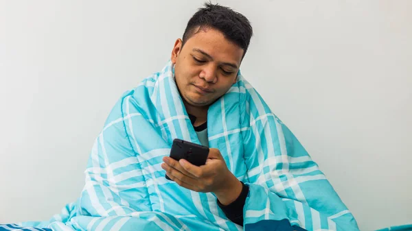 Retrato Homem Asiático Aquecer Sob Cobertor Quarto Segurando Foco Smartphone — Fotografia de Stock
