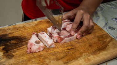 Mutfaktaki tahta kesme tahtasının üzerinde keskin bir bıçakla et doğrayan bir kasabı yakından görebiliriz. Önplana seçici odaklanma.