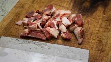 Mutfaktaki tahta kesme tahtasının üzerinde keskin bir bıçakla çiğ sığır eti eti manzarasını kapat. Önplana seçici odaklanma.