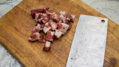 Mutfaktaki tahta kesme tahtasının üzerinde keskin bir bıçakla çiğ sığır eti eti manzarasını kapat. Önplana seçici odaklanma.