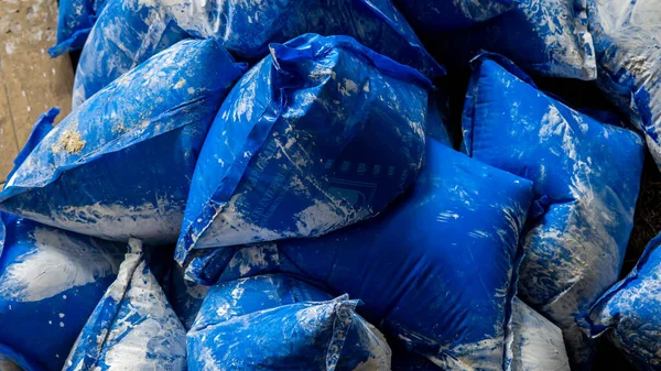 Sungai Buloh, Malaysia - May 16, 2020: Close up view group of blue packaging bag of lime water use for concrete construction on the ground. Make mortar mixes are adhesives used for binding bricks.