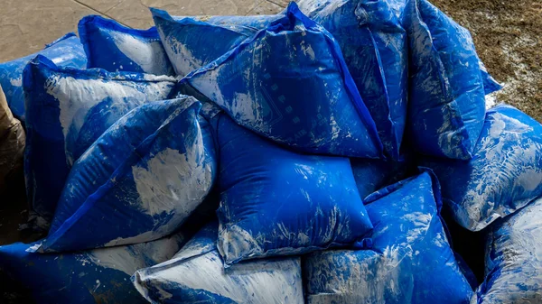 Sungai Buloh, Malaysia - May 16, 2020: Close up view group of blue packaging bag of lime water use for concrete construction on the ground. Make mortar mixes are adhesives used for binding bricks.