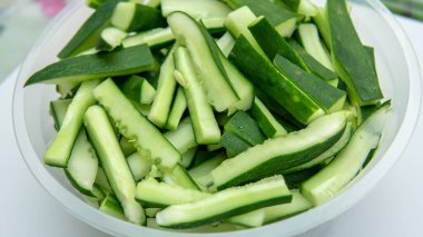 İzole edilmiş beyaz arka planlarda plastik bir bardaktaki çiğ salatalık dilimlerini yakın çekim yapın. Önplana seçici odaklanma.