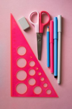 Pembe arka planda çeşitli kırtasiye malzemeleri.