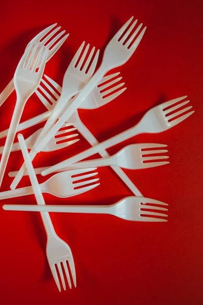 A lot of plastic forks on a red background.