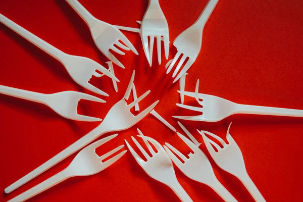 A lot of plastic forks on a red background. — Stock Photo, Image
