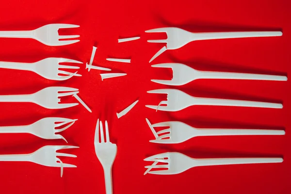 A lot of plastic forks on a red background.