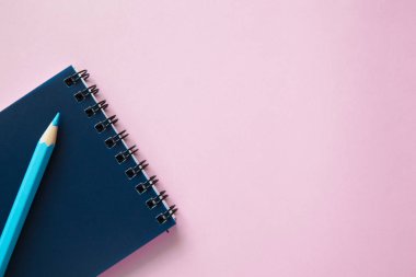 Pembe arka planda bir kalem ve defter..