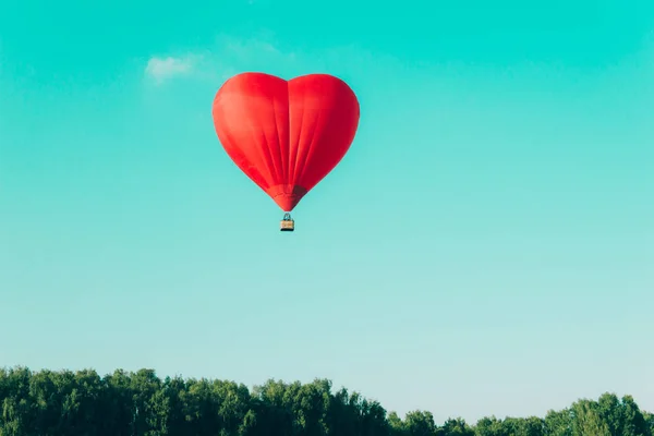 Globo de aire caliente rojo en forma de corazón contra el cielo azul — Foto de Stock