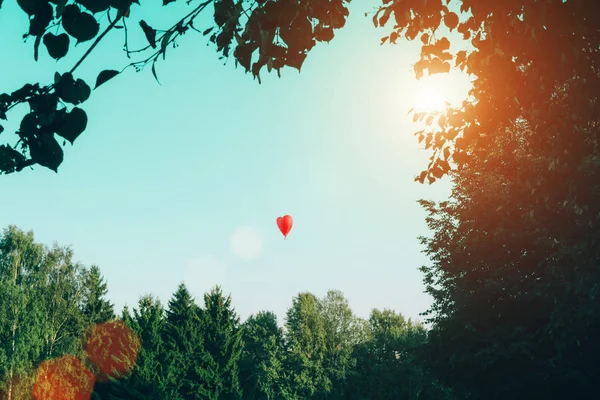 Globo de aire caliente rojo en forma de corazón contra el cielo azul . — Foto de Stock