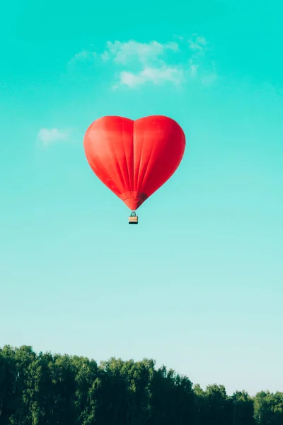 Globo de aire caliente rojo en forma de corazón contra el cielo azul — Foto de Stock