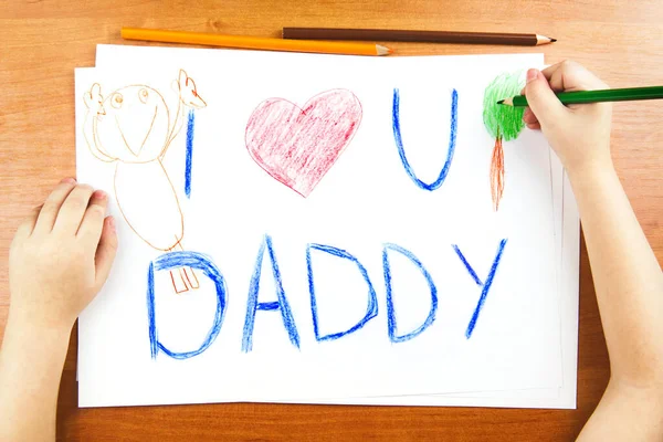 Koncept dne otců. Childs hands drawing words I Love U Daddy, and pencils. — Stock fotografie