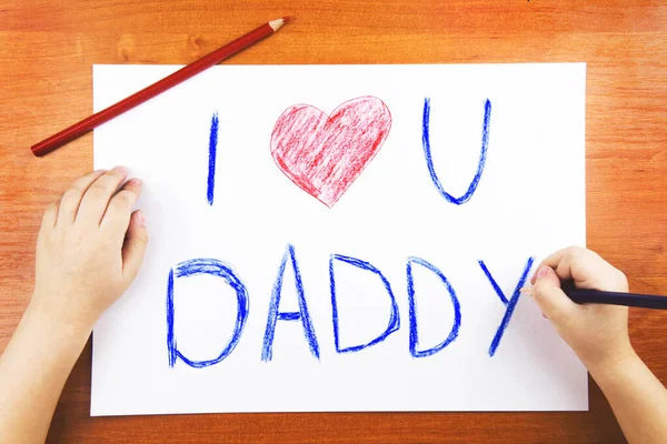 Fathers day concept. Childs hands drawing words I Love U Daddy, and pencils. — Stock Photo, Image