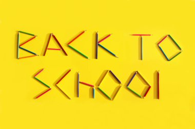 Sarı arka plandaki kalemlerden okula dönüş sözcükleri.