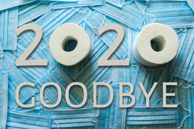Birçok tıbbi maskenin ve 2020 GOODBYE sözcüğünün arka planı beyaz ahşap numaralar, harfler ve tuvalet kağıdı..