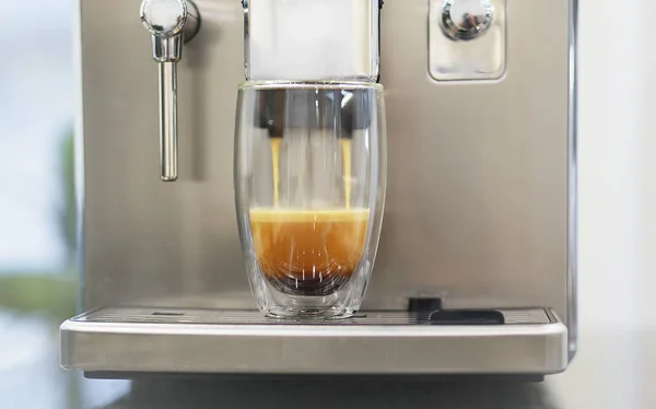 a glass cup of coffee filling on coffee machine