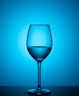 bir bardak su mavi bir arka plan üzerine akrilik cam üzerinde duruyor.