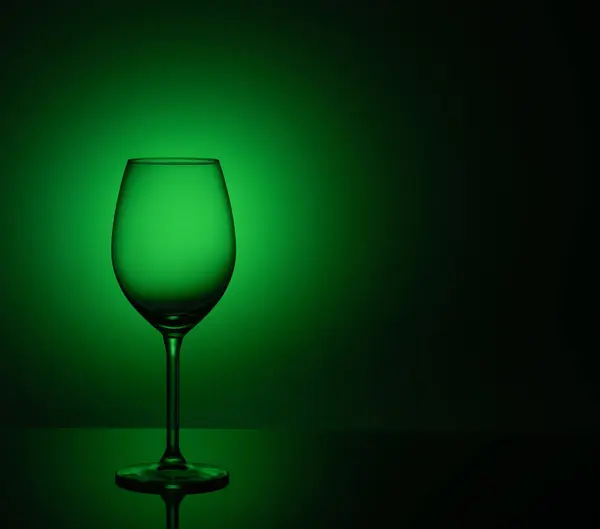 空のワイングラスが緑の背景にアクリル ガラスの上に立つ — ストック写真