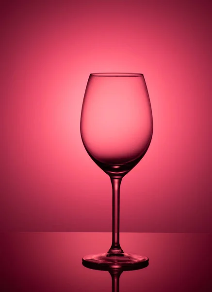 空のワイングラスが赤とピンクの背景にアクリル ガラスの上に立つ — ストック写真
