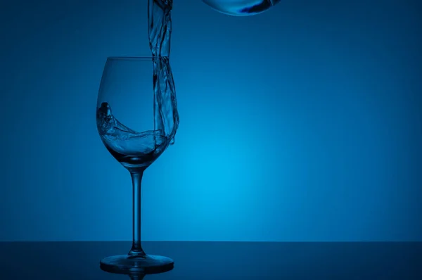 Склянка Води Стоїть Акриловому Склі Синьому Фоні Вода Вливається Склянку — стокове фото