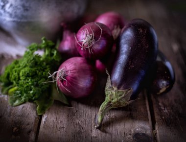 Ahşap bir masada sebzeler, patlıcan, soğan ve salata