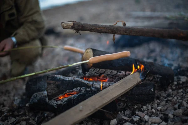 People fry sausages on an open fire — Stock Photo, Image