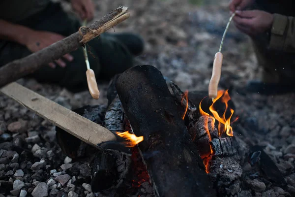 People fry sausages on an open fire — Stock Photo, Image