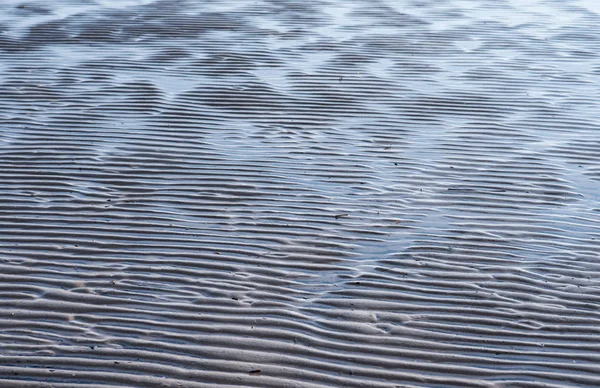 Areia ondulada. a areia brilha ao sol após o refluxo do mar. erupção solar na costa — Fotografia de Stock