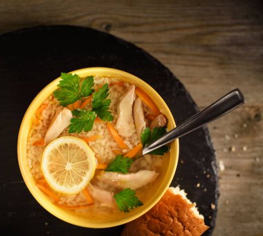 çorba üst görünümü ile plaka. Sarı bir fincan tavuk ile Pirinç çorbası, ekmek bir parça yanında