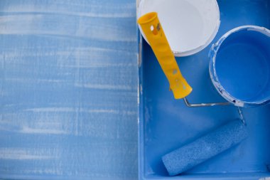 koyu renk üst görünümde mavi ve beyaz boya. duvarlar boyama için sarı bir saplı rulo