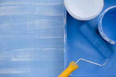 koyu renk üst görünümde mavi ve beyaz boya. duvarlar boyama için sarı bir saplı rulo