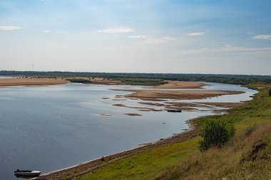 manzara, nehir ve kumlu ada kıyısı, güneş parlıyor.