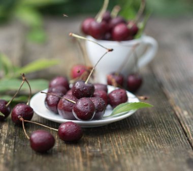 yağmur damlaları kiraz meyveleri ahşap bir masa üzerinde bir tabak yalan