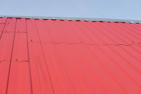 roof covered with red iron sheets against the sky. roof fragment