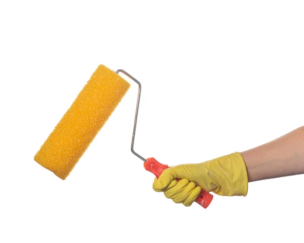 A hand in a yellow glove holds a yellow paint roller with a textured surface for wall decoration, on a white background — Stock Photo, Image